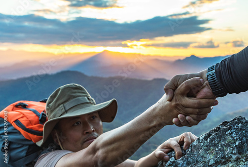 Teamwork helping hand trust assistance on top mountains. The joint work teamwork of two men travelers help each other on top of a mountain climbing team, a beautiful sunset landscape