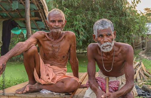 Beautiful image of two tribal Indian farmers or daily wage laborers, old aged yet healthy males sitting together for rest after hardwork and posing for camera while in deep thoughts about their future