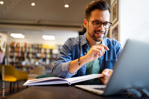 Smiling male student working and studying in a library