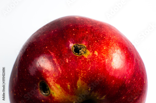 Red wormy spoiled apple on white background. Close up.