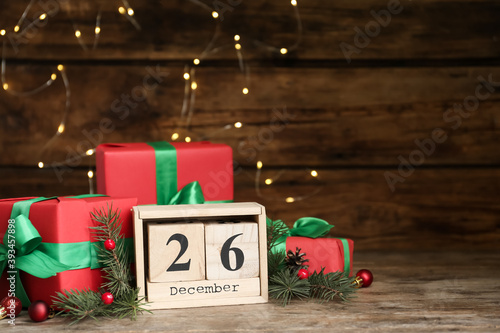 Block calendar with Boxing Day date near gifts on wooden table. Space for text