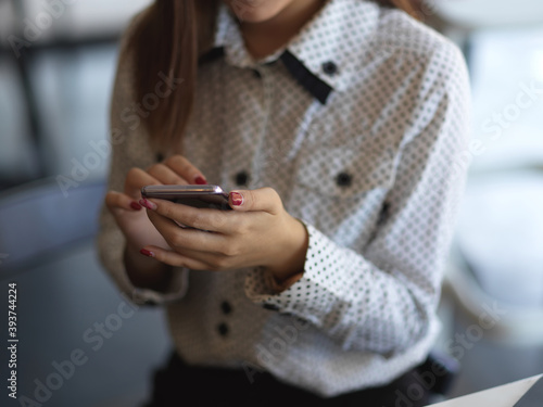 Female hands using smartphone while relaxing in office room