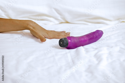 Woman's hand reaching for dildo in bed