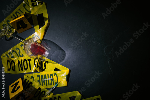 Flat lay composition with evidences and crime scene tape on black slate background, space for text