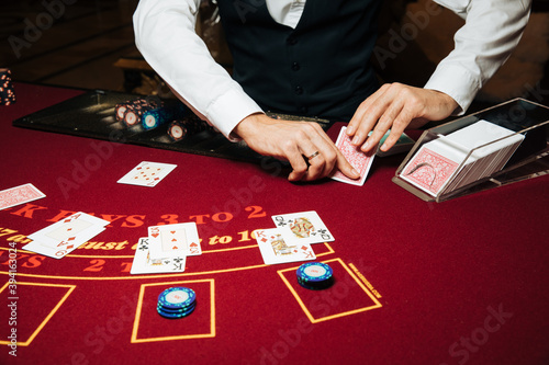 Croupier hands dealing cards on t blackjack poker table, gambling table with cards and chips