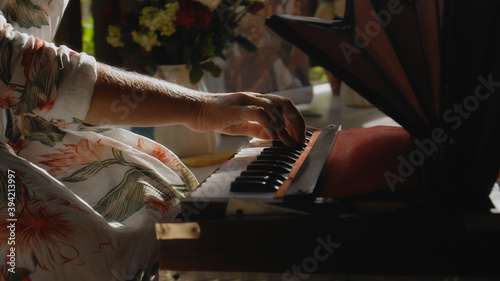 girl sitting on a wooden floor and playing a keyboard ethnic Indian instrument harmonium