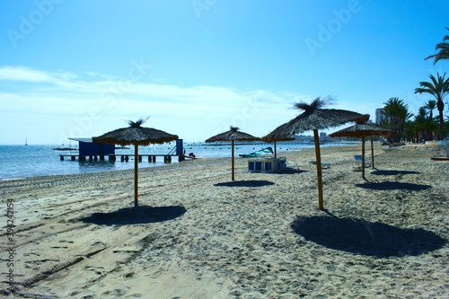 Lo Pagan beach, Mar Menor, Spain. Seaside landscape with rows of sun shad umbrellas. Landscape aspect with copy space. 