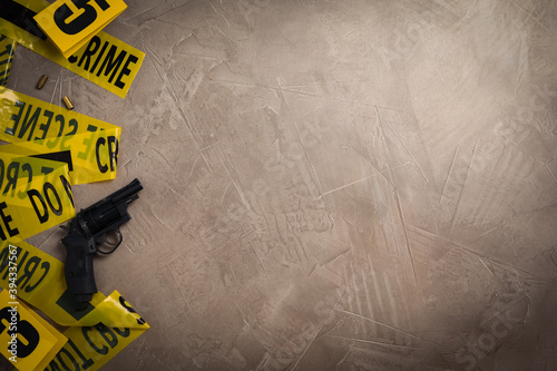 Flat lay with yellow tape, crime scene marker and gun on grey stone background. Space for text
