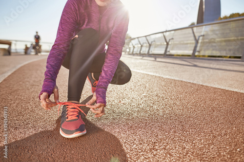 Preparation. Cropped shot of active mature woman wearing sportswear tying her shoelaces while getting ready for running outdoors on a sunny day