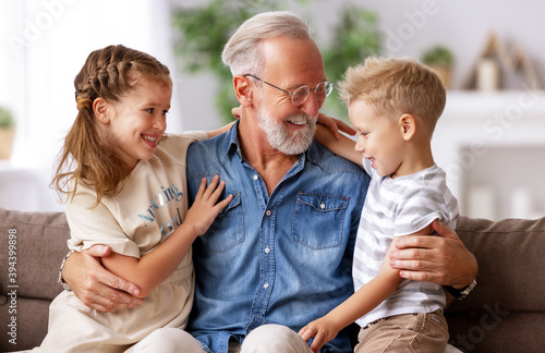 Grandfather hugging grandchildren on sofa.