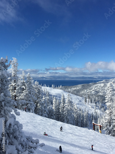 Vertical view of skiers on a ski slope at a resort in winter on a sunny day with blue skies, ,with Lake Tahoe in the background