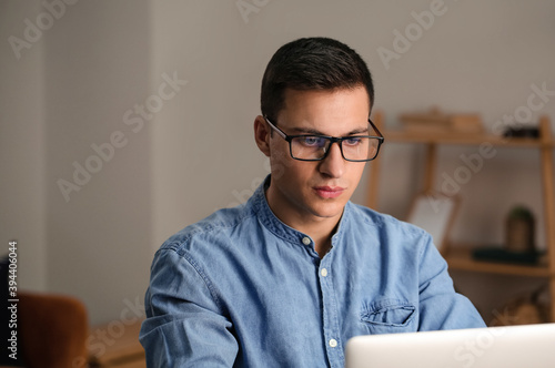Young man working on laptop in office late in evening