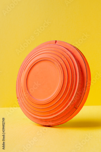 Clay disc target for skeet shooting standing edgewise against the colorful yellow background. Clay pigeon shooting