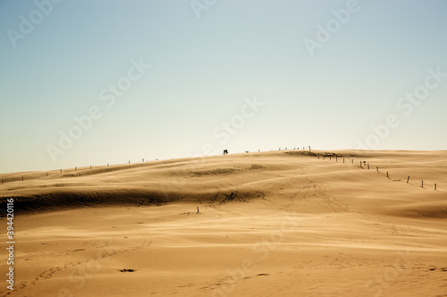 Krajobraz pustynny błękitne niebo i ruchome piaski z sylwetką idącego człowieka w pięknym świetle zachodzącego słońca 