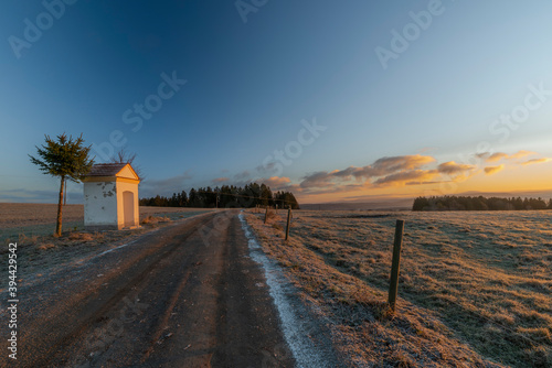 Chapel near path to Rybnik village with color sunrise light and frosty air
