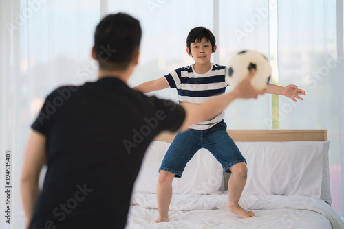 dad and son enjoy playing soccer football together in bedroom at home