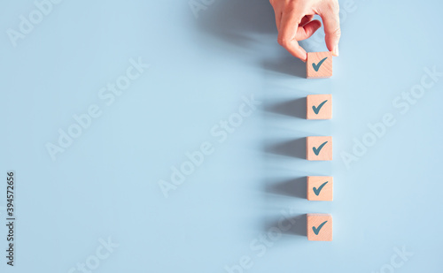 Wood cube with check mark on blue background, Checklist concept, Copy space.