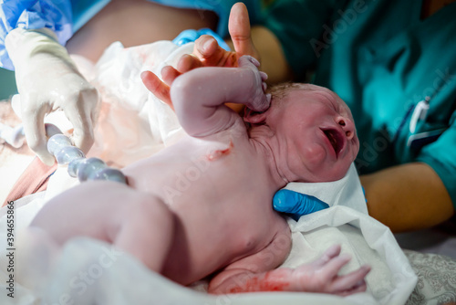 Crying newborn baby boy still with umbilical cord.