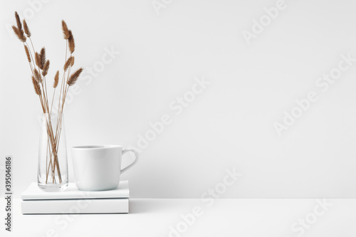 Mug and transparent vase with flowers on a white background. Eco-friendly materials in the decor of the room, minimalism. Copy space, mock up
