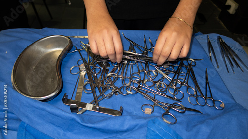 Manos de mujer manipulando instrumental quirúrgico sobre mesa con tela azul