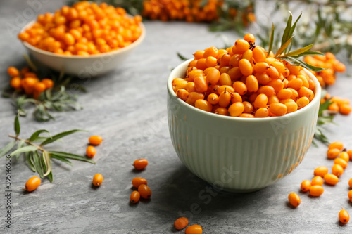 Fresh ripe sea buckthorn in bowl on grey table