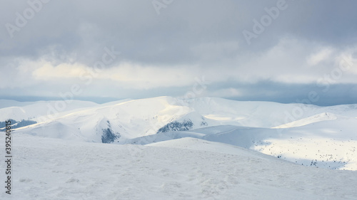 Snow-covered mountain slopes under a cloudy sky.