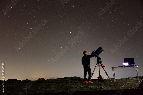 Young woman fond of astronomy observing through her telescope