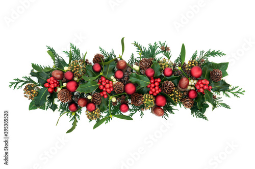 Christmas arrangement with red bauble decorations, holly, mistletoe, ivy, acorns & cedar cypress on white background. Xmas and New Year decorative display. Flat lay, top view, copy space.