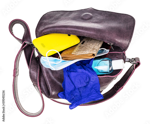 top view of ladies bag with protective items, wallet and smartphone isolated on white background