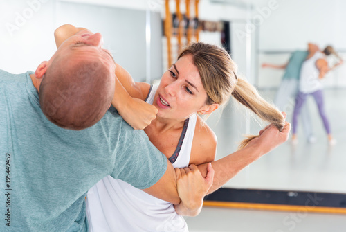 Young woman practicing elbow blow with male partner during self defense course in gym..