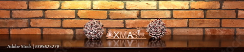 Xmas inscription and Christmas decorations on the background of an old brick wall.