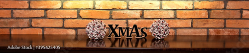 Xmas inscription and Christmas decorations on the background of an old brick wall.
