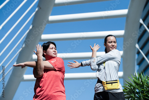 Woman with different size wearing sportswear do stretching exercise outdoors together. Portrait of plus-size woman exercise. Overweight woman, sports, healthcare, weight loosing, fitness, well-being.