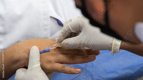 Poniendo aguja de suero sobre brazo de paciente