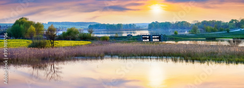 Spring landscape with river and picturesque sky reflected in water, sunset on the river, panorama