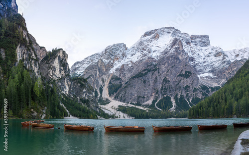 A panoramic view of the lake Pragser Wildsee in the Dolomites with a chain of boats, mountains and woods in autumn in South Tyrol, Italy.