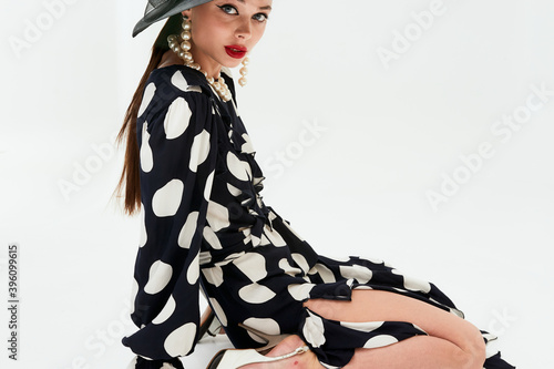 Woman with black hat wide and polka dot dress posing for fashion on a white background vertical photos