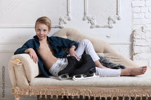Young figure skater dressed in white jeans and blue shirt relaxing on sofa