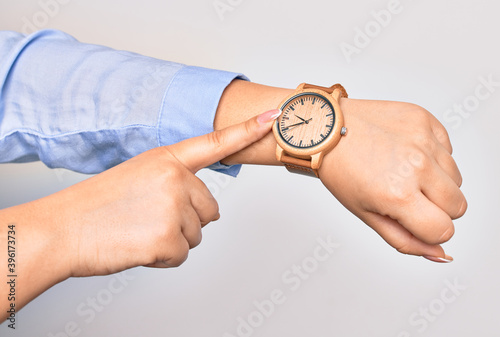Hand of caucasian young businesswoman wearing wristwatch. Pointing with finger to watch over isolated white background