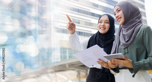 Successful Muslim businesswomen are discussing work to achieve common goals while outdoors.