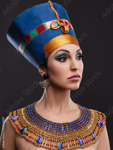 closeup studio portrait of a beautiful woman with brown eyes and evening make-up in the image of Queen Nefertiti, crown, necklace