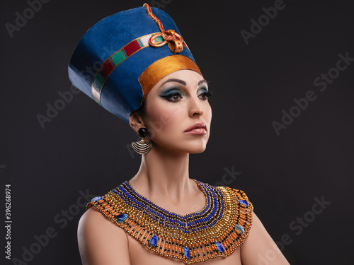 closeup studio portrait of a beautiful woman with brown eyes and evening make-up in the image of Queen Nefertiti, crown, necklace