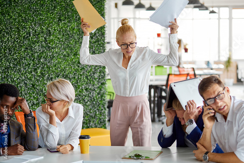 furious female director dissatisfied with work, she yells at emplyees holding papers documents in hands, bad work concept