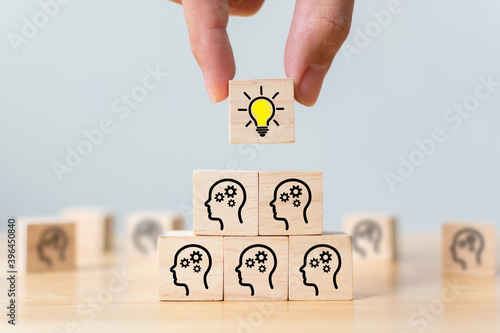 Concept creative idea and innovation. Hand picked wooden cube block with head human symbol and light bulb icon