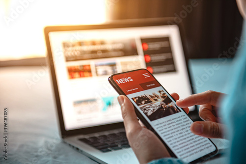 Online news on a smartphone. Mockup website. Woman reading news or articles in a mobile phone screen application at home. Newspaper and portal on internet.