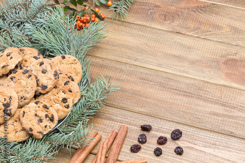 Cookies with raisins among fir branches. Raisins and cinnamon sticks on table