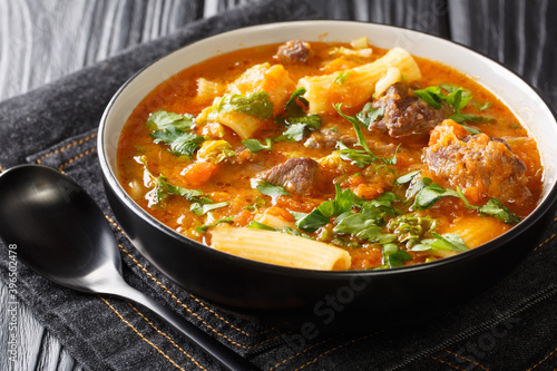 Soup Joumou or Haitian Beef and Pumpkin Soup is a famous mildly spicy soup prepared with beef and vegetables and also rigatoni pasta closeup in the plate on the table. Horizontal