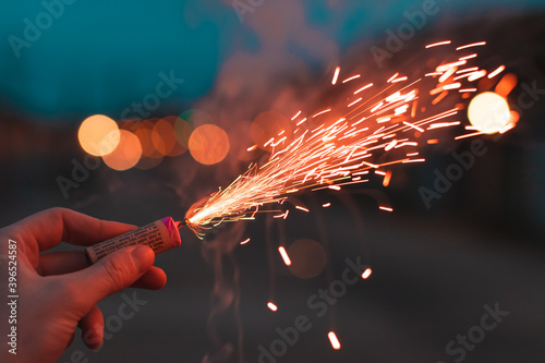 Young Man Lighting Up Firecracker in his Hand Outdoors in Evening. Guy Getting Ready for New Year Fun with Fireworks or Pyrotechnic Products - CloseUp Shot