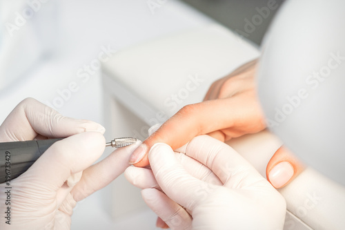 Manicurist removes nail polish uses the electric machine of the nail file during a manicure