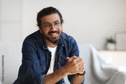Young Indian Man With Eyeglasses And Dental Braces Posing In Home Interior